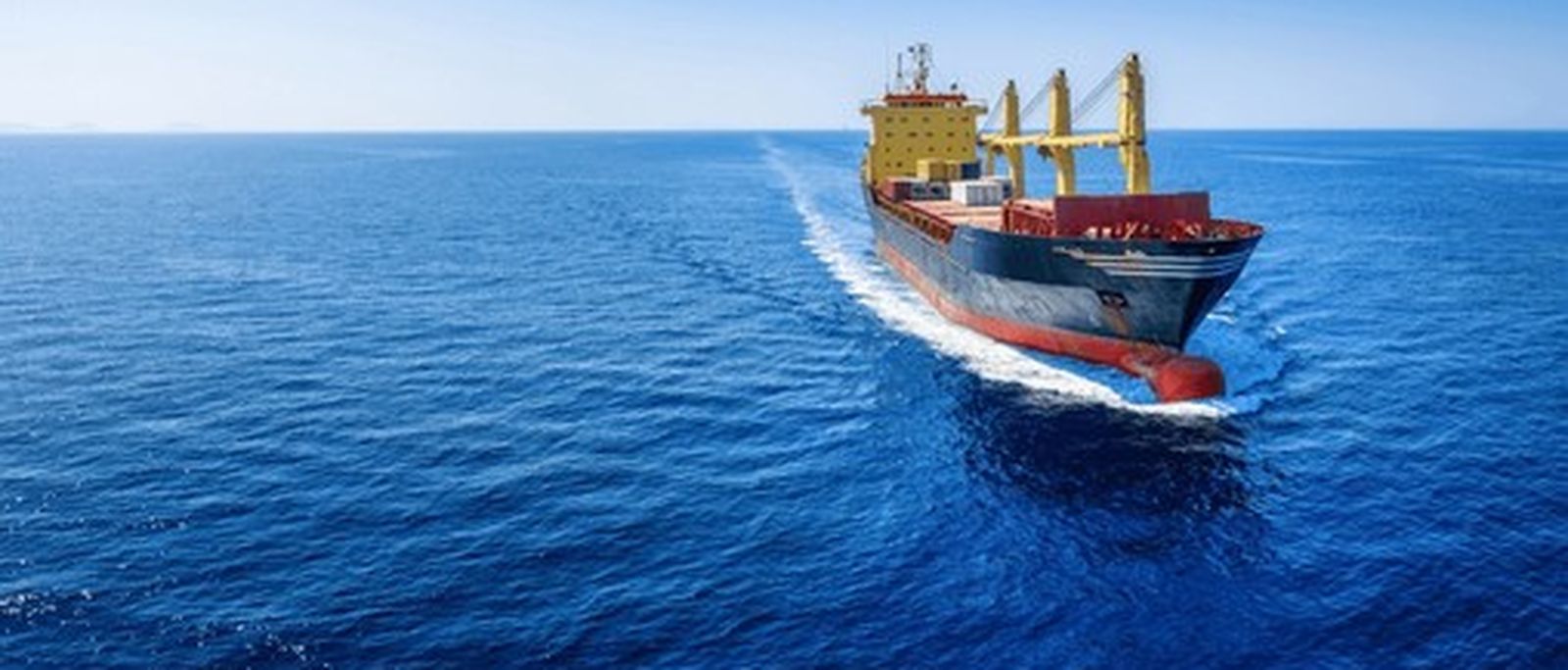 A loaded bulk carrier at anchor in open water.