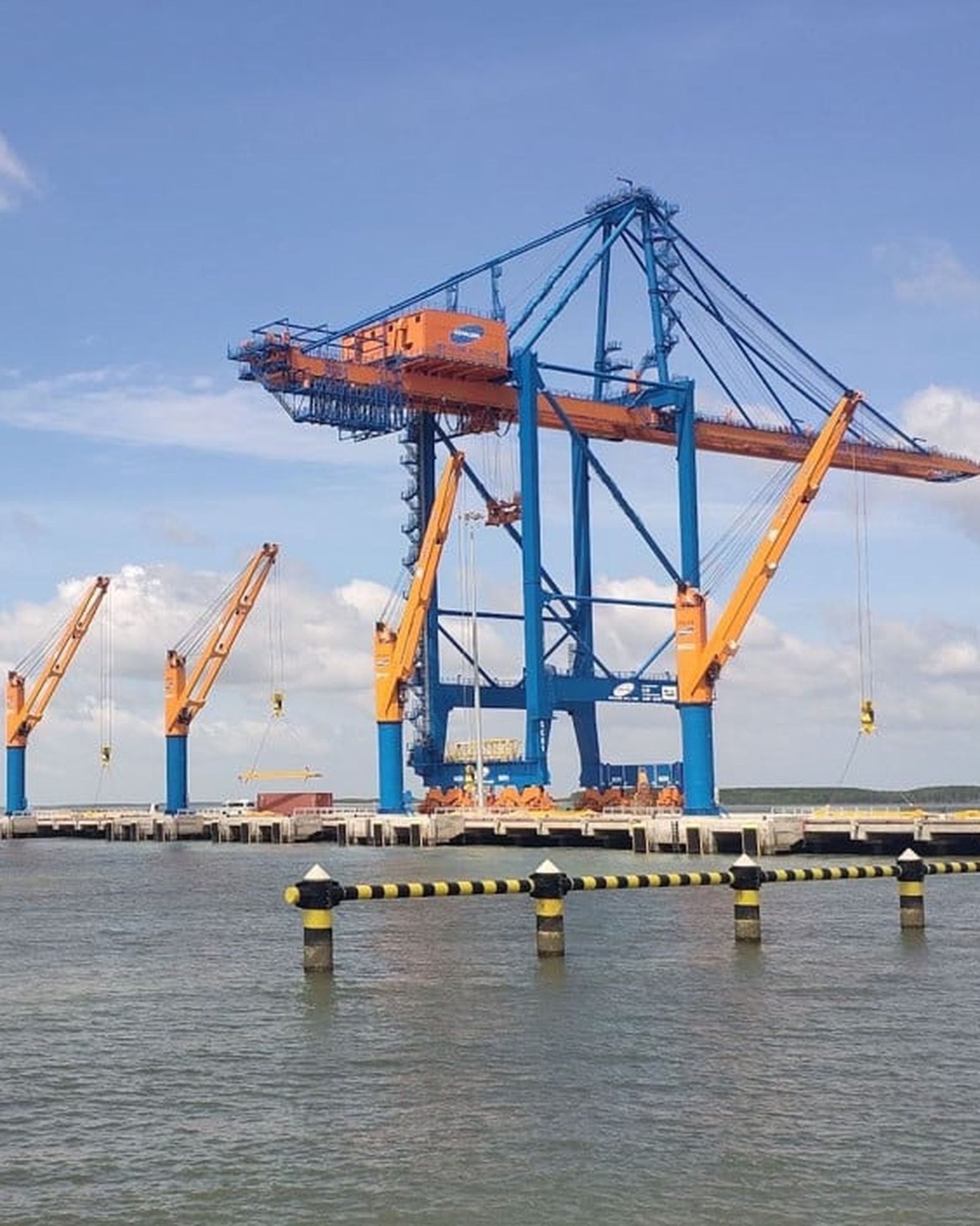 A geared general cargo vessel working alongside a quay.